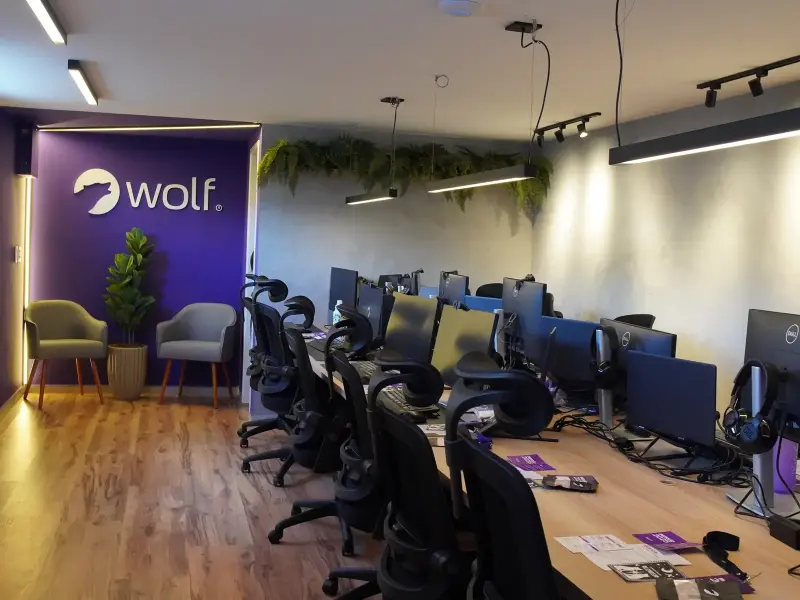Escritório Wolf Aceleradora em Caruaru. Vista panorâmica com estações de trabalho e parede com logo